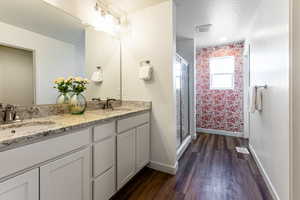 Primary bathroom featuring hardwood / wood-style flooring, a shower with door, and vanity