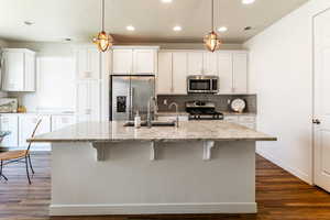 Kitchen featuring hanging light fixtures, light stone countertops, and stainless steel appliances