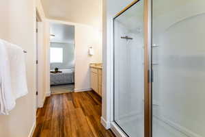 Primary bathroom with hardwood / wood-style floors, a shower with door, and vanity