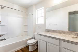 Full bathroom with  shower combination, vanity, toilet, and hardwood / wood-style flooring