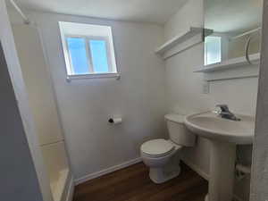 Full bath with baseboards, toilet, wood finished floors, walk in shower, and a sink