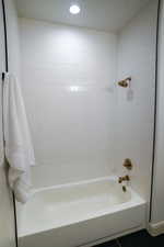 Bathroom 2 is a full bath with white cabinetry, full steel tub/shower, with tile to the ceiling.