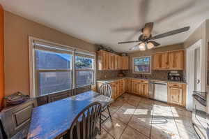 Kitchen featuring range, stainless steel dishwasher, ceiling fan, and a wealth of natural light