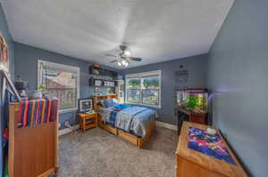 Carpeted bedroom featuring a textured ceiling and ceiling fan