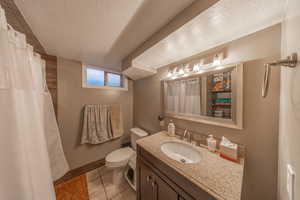 Bathroom featuring tile patterned floors, a textured ceiling, vanity, and toilet