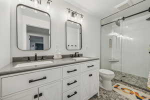 Bathroom with walk in shower, tile patterned flooring, vanity, and toilet