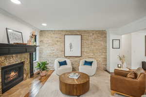 Living room with ornamental molding, hardwood / wood-style flooring, and a stone fireplace