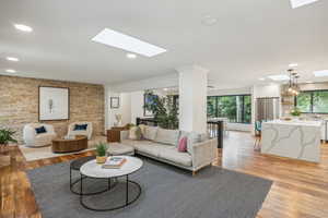 Living room with an inviting chandelier, light hardwood / wood-style flooring, and a skylight