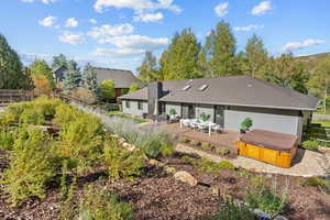 Rear view of property featuring a hot tub and a patio area