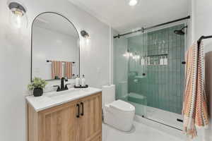 Bathroom featuring tile patterned floors, a shower with door, vanity, and toilet