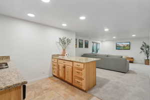 Kitchen featuring light stone counters, kitchen peninsula, and light colored carpet