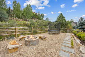 View of yard featuring a trampoline and an outdoor fire pit