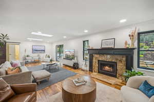 Living room with light wood-type flooring, crown molding, a fireplace, and a skylight