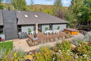 Rear view of house featuring a deck with mountain view and a hot tub