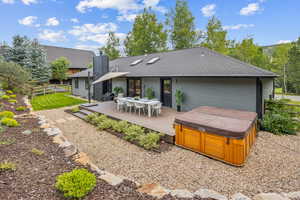 Rear view of property featuring a hot tub and a wooden deck