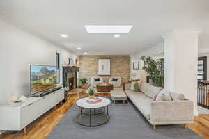 Living room with crown molding, a skylight, and hardwood / wood-style flooring