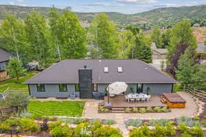 Rear view of property with central AC unit, a yard, and a deck with mountain view