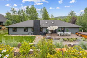 Back of house featuring a lawn, cooling unit, and a deck with mountain view