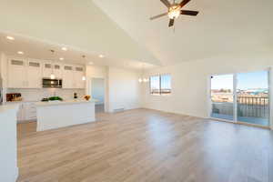 Kitchen with light wood finished floors, visible vents, glass insert cabinets, stainless steel microwave, and light countertops