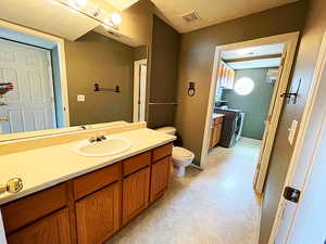 Bathroom with vanity, separate washer and dryer, and toilet