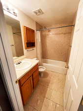 Full bathroom with a textured ceiling, shower / tub combo with curtain, vanity, and toilet