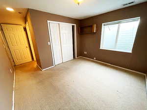 Unfurnished bedroom with light colored carpet and a closet