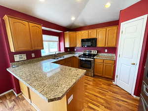 Kitchen featuring wood-type flooring, kitchen peninsula, sink, and stainless steel range with electric cooktop