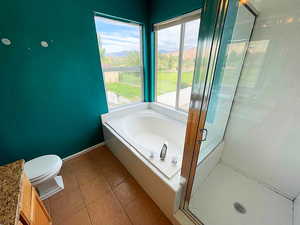 Bathroom with shower with separate bathtub, toilet, and tile patterned floors