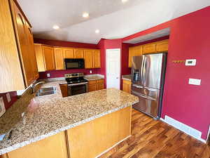 Kitchen featuring light stone countertops, stainless steel appliances, light wood-type flooring, and kitchen peninsula