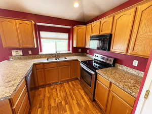 Kitchen with appliances with stainless steel finishes, sink, and dark hardwood / wood-style flooring