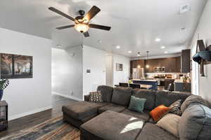 Living room with ceiling fan and dark hardwood / wood-style flooring