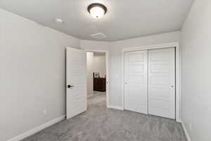 Unfurnished bedroom with light carpet, a textured ceiling, and a closet