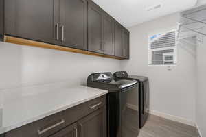 Laundry room with washing machine and clothes dryer, cabinet space, and light tile patterned floors
