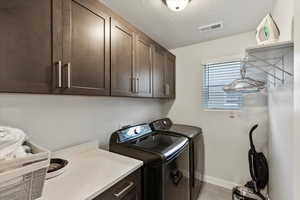 Washroom with cabinets, a textured ceiling, and separate washer and dryer