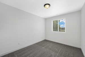 Unfurnished room with dark colored carpet and baseboards