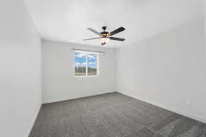 Carpeted spare room featuring baseboards and a ceiling fan