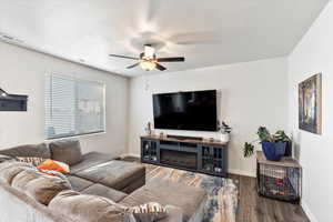 Living room with ceiling fan, a textured ceiling, and dark hardwood / wood-style flooring