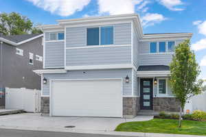 View of front of property featuring stone siding, concrete driveway, and a garage