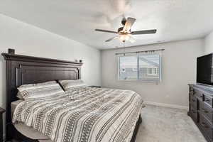 Bedroom with a textured ceiling, ceiling fan, and light colored carpet