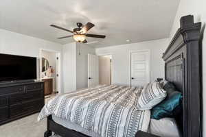 Carpeted bedroom featuring ceiling fan, a textured ceiling, and connected bathroom