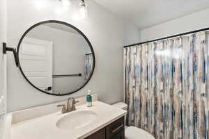 Bathroom with a shower with curtain, vanity, and toilet