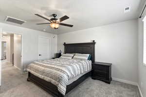 Carpeted bedroom featuring ceiling fan and a textured ceiling