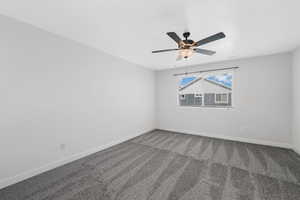 Carpeted empty room featuring baseboards and a ceiling fan