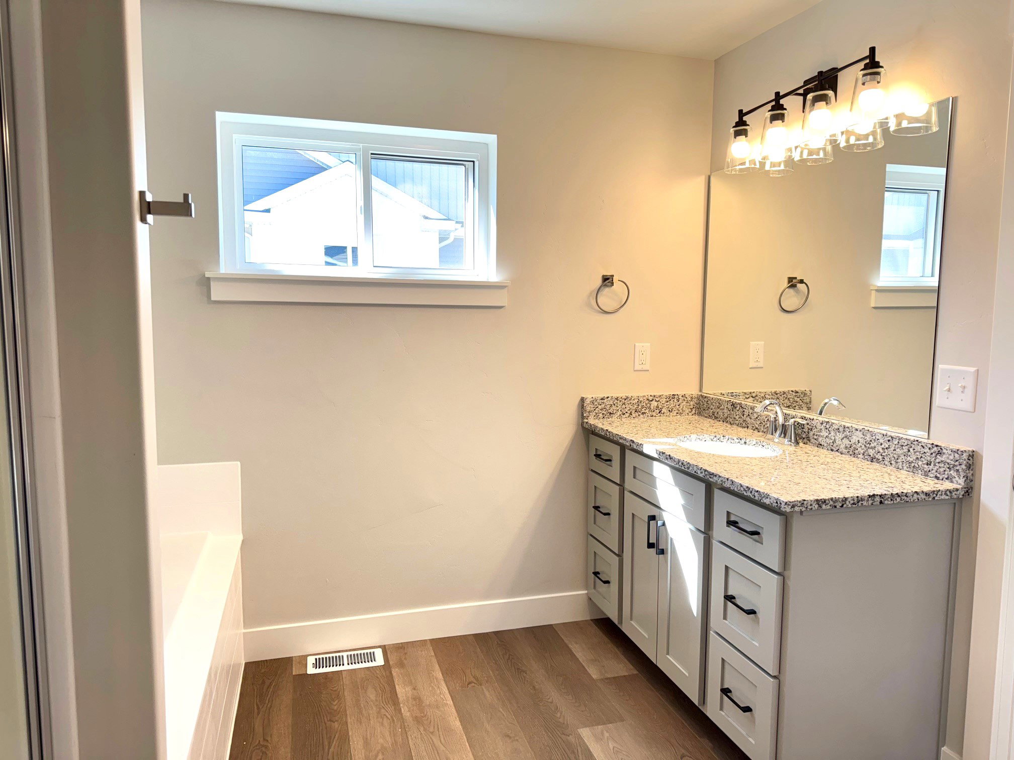 Bathroom featuring vanity, hardwood / wood-style floors, a tub, and a healthy amount of sunlight