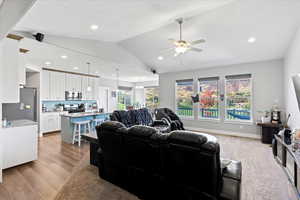 Living room with ceiling fan, vaulted ceiling, and hardwood / wood-style floors