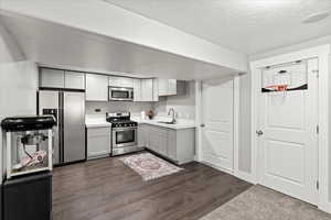 Kitchen featuring sink, gray cabinetry, a textured ceiling, stainless steel appliances, and dark hardwood / wood-style floors