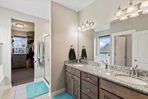 Bathroom featuring tile patterned flooring, a shower with door, and vanity