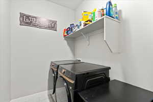 Laundry room with a textured ceiling, light tile patterned flooring, and washing machine and dryer