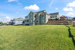 Rear view of house with a balcony and a lawn