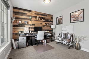 Home office with carpet and wood walls